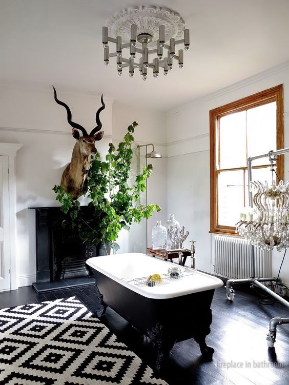 a vintage bathroom with a black floor, a vintage fireplace, taxidermy and greenery, a chic chandelier and a printed rug