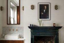 a vintage bathroom with a built-in vanity and a mirror, a vintage fireplace with a teal mantel, an oval tub, a print and some decor