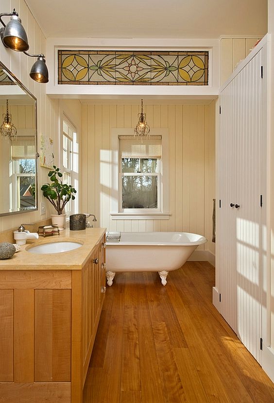a vintage rustic bathroom with a stained floor and vanity, with painted planked wlals and a ceiling, with sconces and a vintage tub