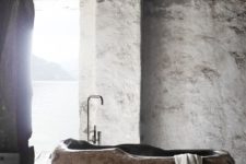 a wabi-sabi bathroom with plaster walls and a bathtub cut out of a stone slab is a unique idea to go for