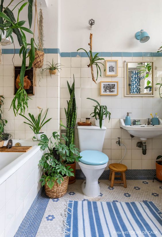 a bright blue and white bathroom with lots of greenery in various pots here and there feels alive