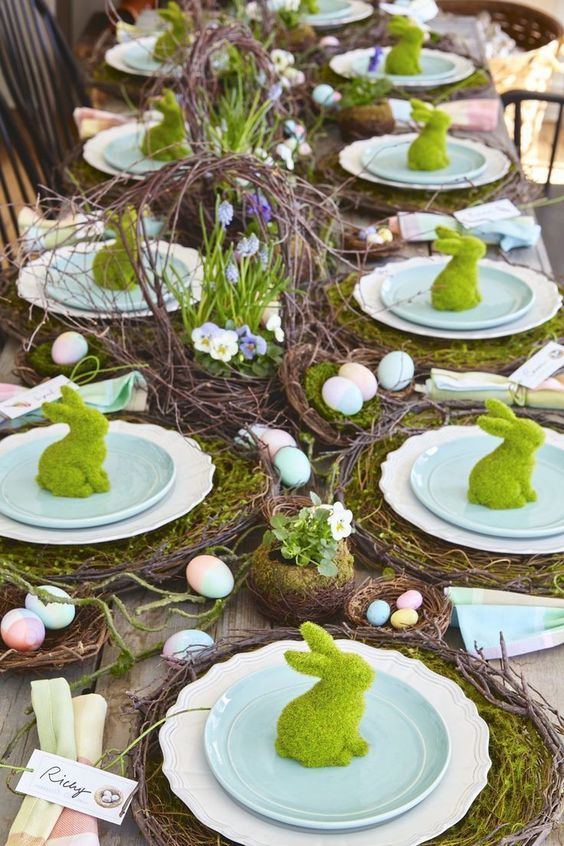 a bright rustic Easter table setting with vine placemats and moss, faux nests with colorful eggs, a vine centerpiece with blooms