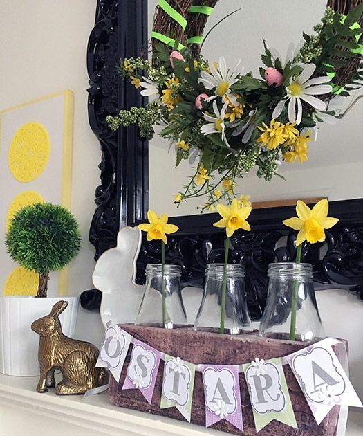 a bright spring mantel with an Easter bunting, some daffodils in bottles, bunnies and a green topiary