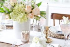 a bright spring tablescape with wicker chargers, checked napkins, a pastel floral centerpiece and some mercury glass accessories