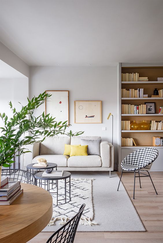 a chic and neutral living room accessorized with yellow pillows and greenery to make it feel like spring