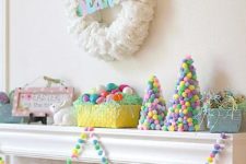 a colorful and fun Easter mantel with a coffee filter wreath and colorful letters, colorful pompom cones, colorful eggs and a garland