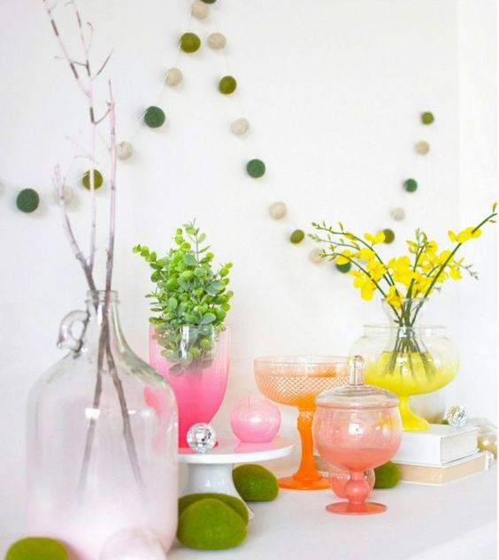 a colorful spring display with moss eggs, bright neon ombre vases and blooming branches and greenery