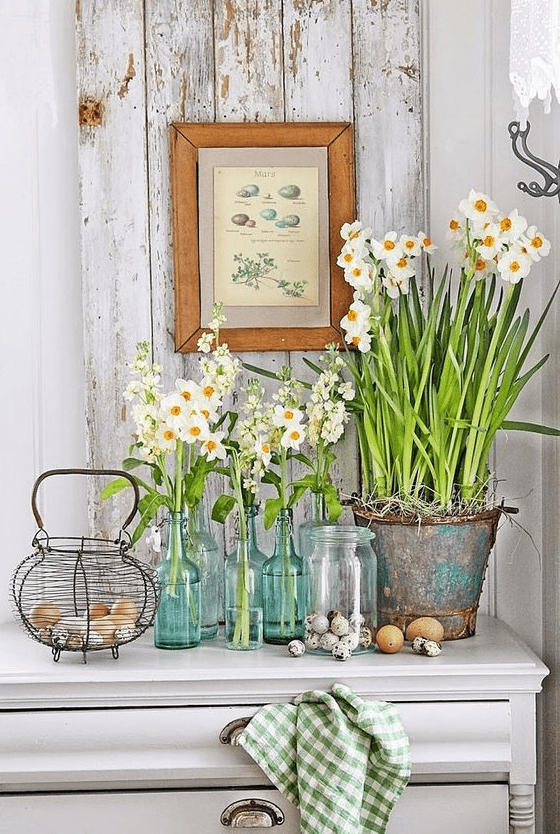 a console styled with fresh blooms in clear vases and a bucket, a nest with real eggs is great for spring and Easter