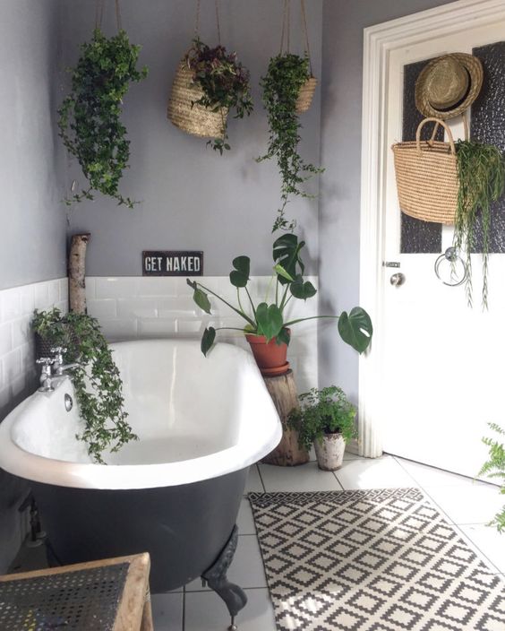 a contemporary monochromatic bathroom with lots of suspended greenery and some planters on the floor