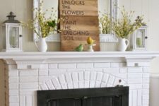 a cozy and simple spring mantel with yellow blooms in jugs, a wood sign and some fake birdies on stands