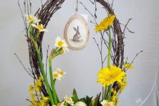a cute Easter flower arrangement with a basket o vine, yellow blooms and foliage, some eggs and a nest with yellow eggs