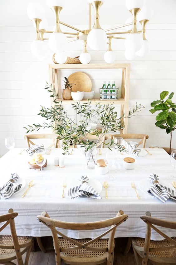 a fresh farmhouse tablescape with striped napkins, an olive branch centerpiece and gold cutlery
