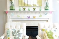 a fun Easter mantel with yellow rose arrangements, a colorful bunny artwork, a bird garland and bottles