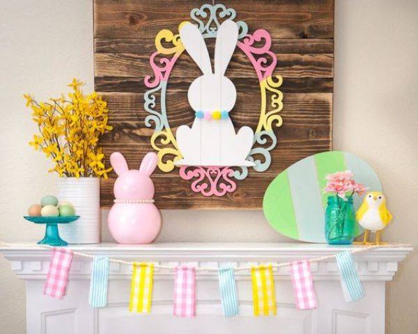 a funny Easter mantel with a bunny sign with a frame, fake bunnies, birds and a cardboard egg