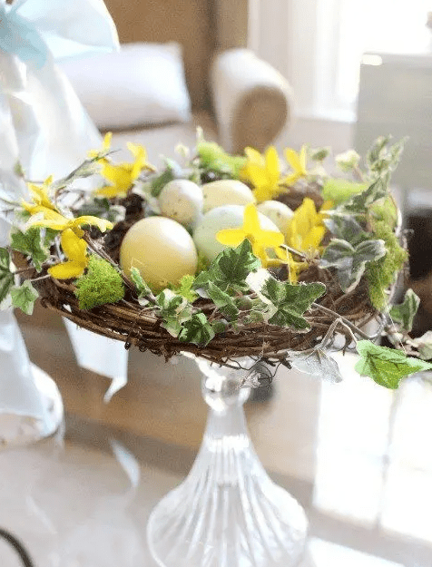 a glass stand with a nest, faux leaves and speckled eggs is a chic and cool rustic Easter decoration that you can make yourself