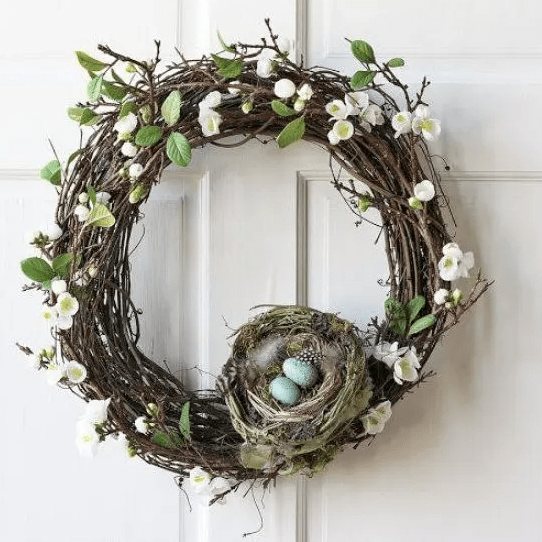 a grapevine spring wreath with faux flowers and leaves, a nest with feathers and eggs is a cool decoration that you can easily DIY
