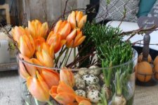 a jar with orange tulips, bulbs and speckled eggs is a bold Easter centerpiece