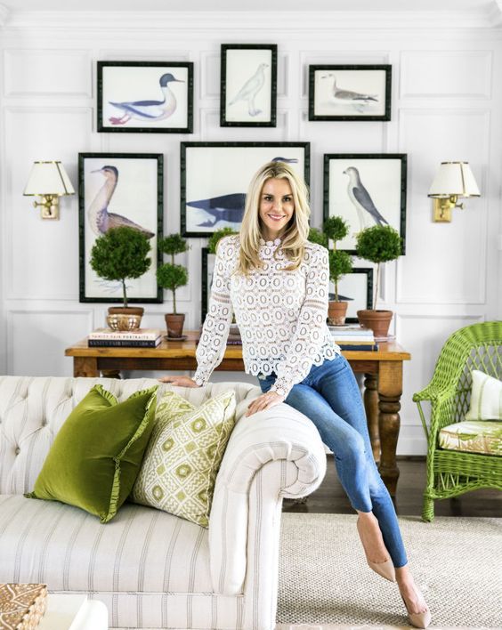 a living room spruced up for spring - with green topiaries and green pillows and a chair is elegant and refreshing