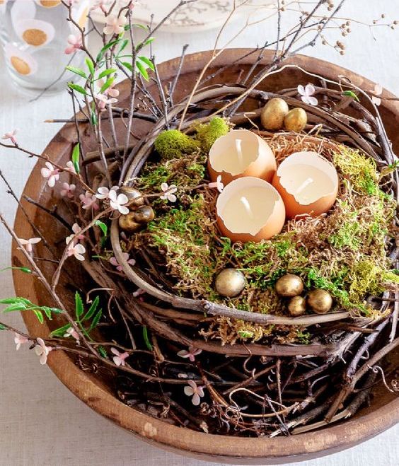 a lovely Easter centerpiece of a vine nest, moss, egg shell candles and gold eggs plus faux blooms is amazing