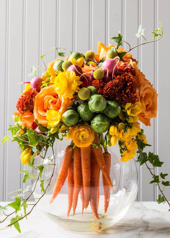 a lush spring or Easter flower arrangement of yellow, red and orange blooms, cabbage and carrots in the aquarium