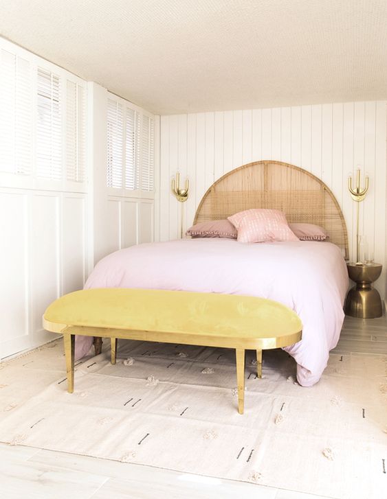 a marigold upholstered bench and pink bedding make this neutral space feel very spring-like