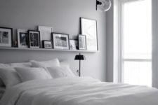 a monochromatic Nordic bedroom with hanging lamps, a white bed, a ledge with artworks and black lamps
