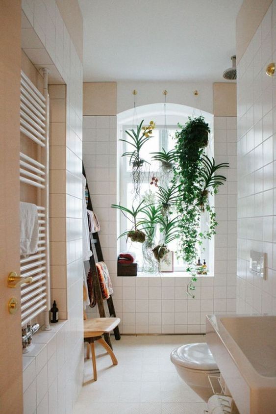a neutral bathroom with potted plants and kokedama on the window that refresh this space
