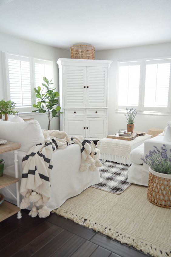 a neutral farmhouse living room with neutral furniture, printed textiles, potted greenery and some lavender feels like spring