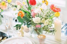a neutral runner, a colorful floral centerpiece, candles, gilded cutlery and pastel plates for a vibrant look