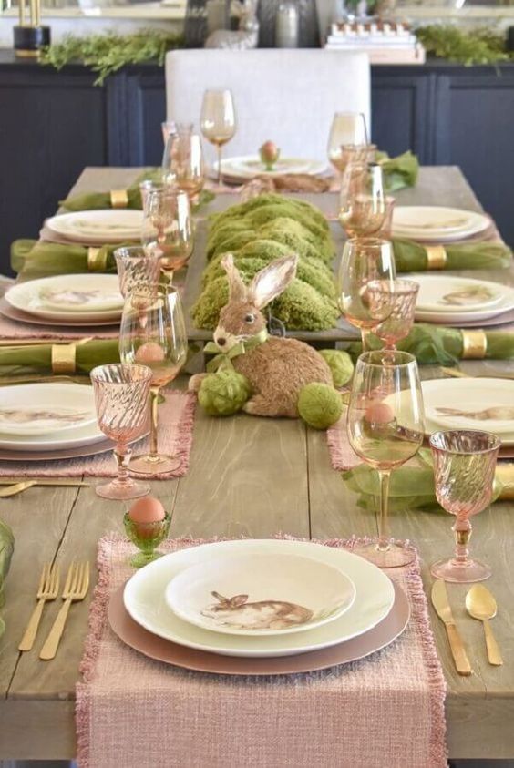 a pastel Easter tablescape with pink runners, green napkins, moss, a bunny and pink glasses is lovely