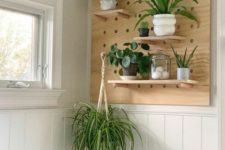 a pegboard piece with shelves attached to the wall for storage and potted greenery and succulents for a cool look