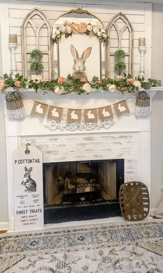 a pretty rustic Easter mantel with a burlap banner, baskets, greenery and faux bloom garlands, a bunny artwork, some greenery topiaries and candles