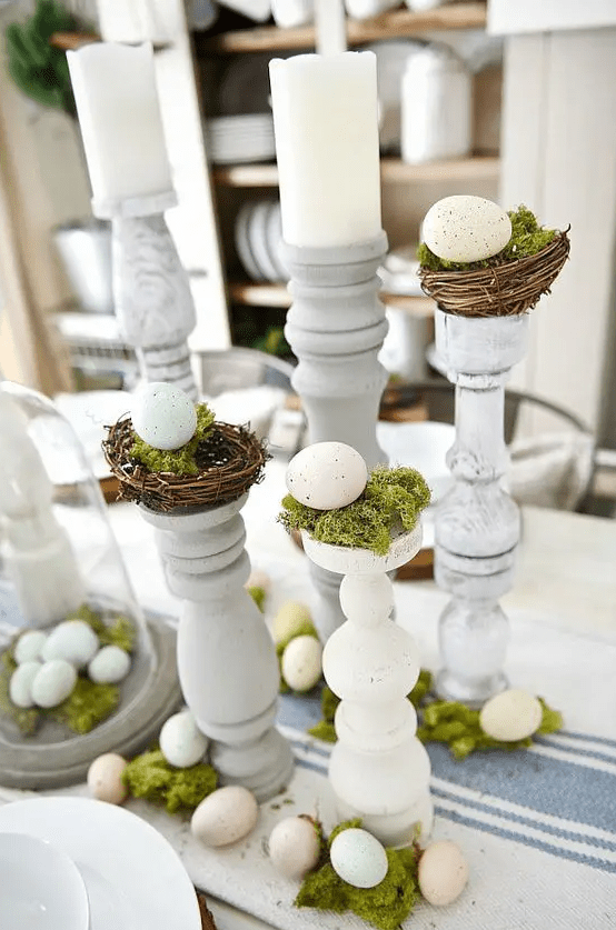 A rustic Easter table decoration made of candlesticks, nests with moss and eggs is a cool solution for a rustic table decoration or console table