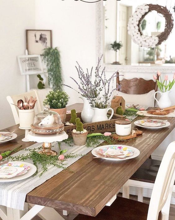 a rustic Easter table setting with a wooden tray with lavender and greenery, moss bunnies, greenery and printed plates