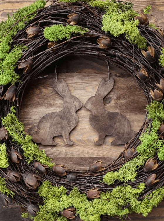a rustic grapevine wreath with wooden bunnies and moss is a cool and catchy decoration for a rustic space