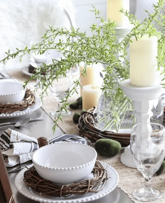 a rustic spring or Easter tablescape with greenery, candles, vine wreaths, wooden napkin rings and moss eggs