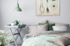a subtle spring bedroom with grey and green bedding, a vintage botanical poster and a green lamp is a tender space