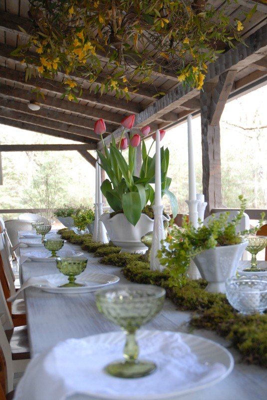 a thrifted spring table setting with pink tulips, grene glasses, a moss runner and a greenery centerpiece