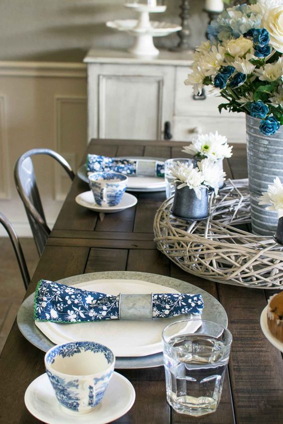 a vintage-inspired sprign table setting with navy printed napkins, a white and blue floral centerpiece and printed porcelain