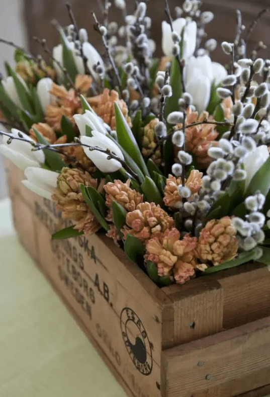 a wooden crate with fresh spring blooms, willows and leaves is a gorgeous rustic decoration for Easter and spring