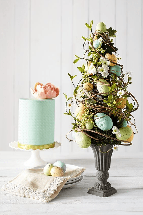an Easter flower arrangement designed as a tree - with vines, greenery, blooms and pastel eggs