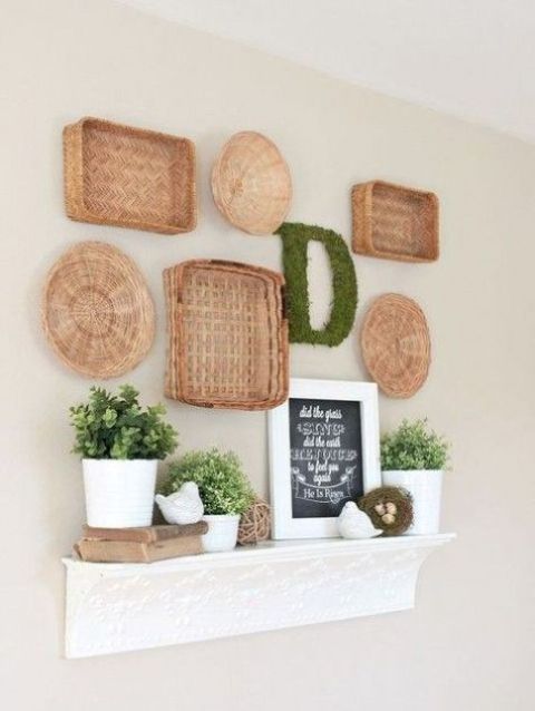 faux mantel decorated for spring with baskets on the wall, a moss monogram, potted greenery and fake birds and eggs
