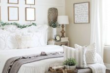 potted greenery and a faux greeneyr garland make this neutral farmhouse bedroom refreshed and spring-like