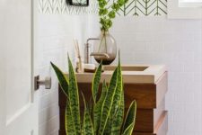 refresh the bathroom with a statement plant and some greenery branches in a vase for a cool look