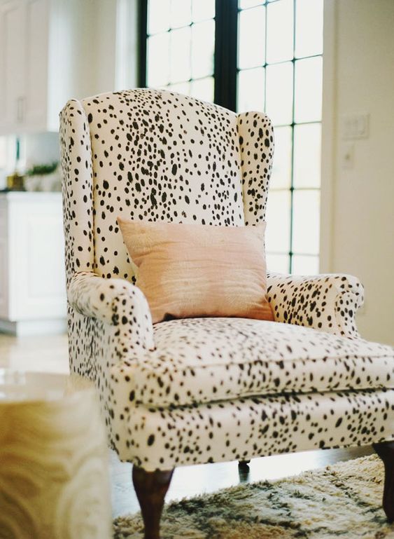 a Dolmatin printed chair with a peachy pillow is a catchy and stylish accent to the space, it's a bold and pretty idea