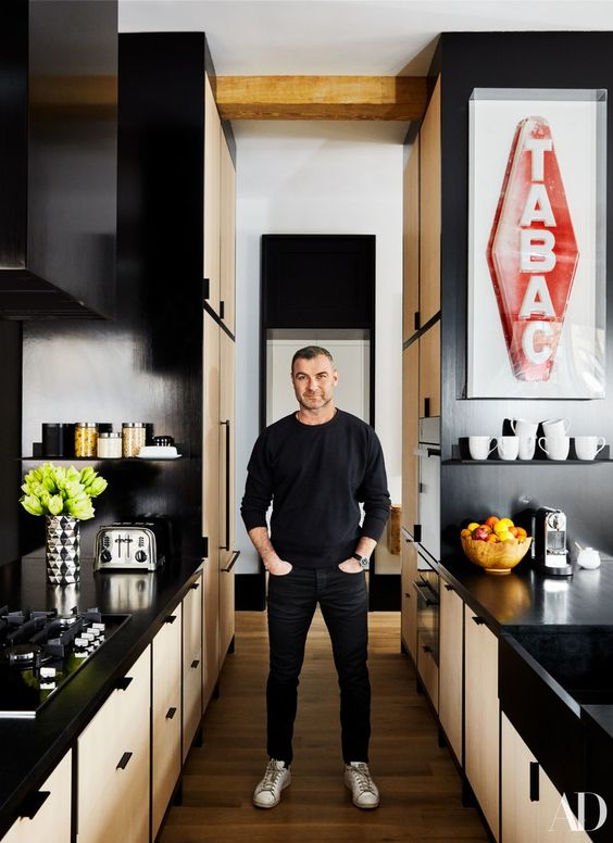 a black and light-colored wooden kitchen with sleek metal countertops plus signs and bold blooms