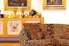 a bold vintage living room with a leopard print sofa, a red rug, a chic painted credenza, dark and moody art is amazing