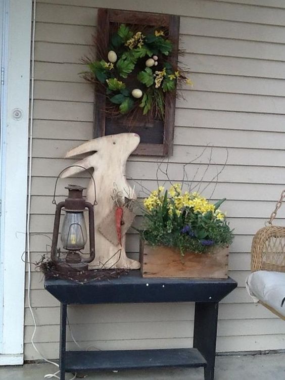 a bunny cutout of plywood, potted blooms, a wreath with fake greenery, eggs and branches