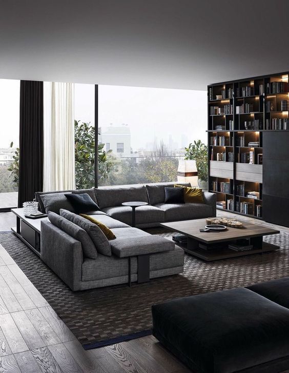 a contemporary dark living room with a large storage unit, an L-shaped sofa, a rug, a wooden coffee table and curtains