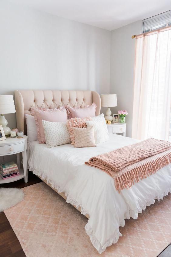 a cute and sweet feminine bedroom with grey walls, a neutral bed with pink ruffled bedding, a pink rug and white nightstands